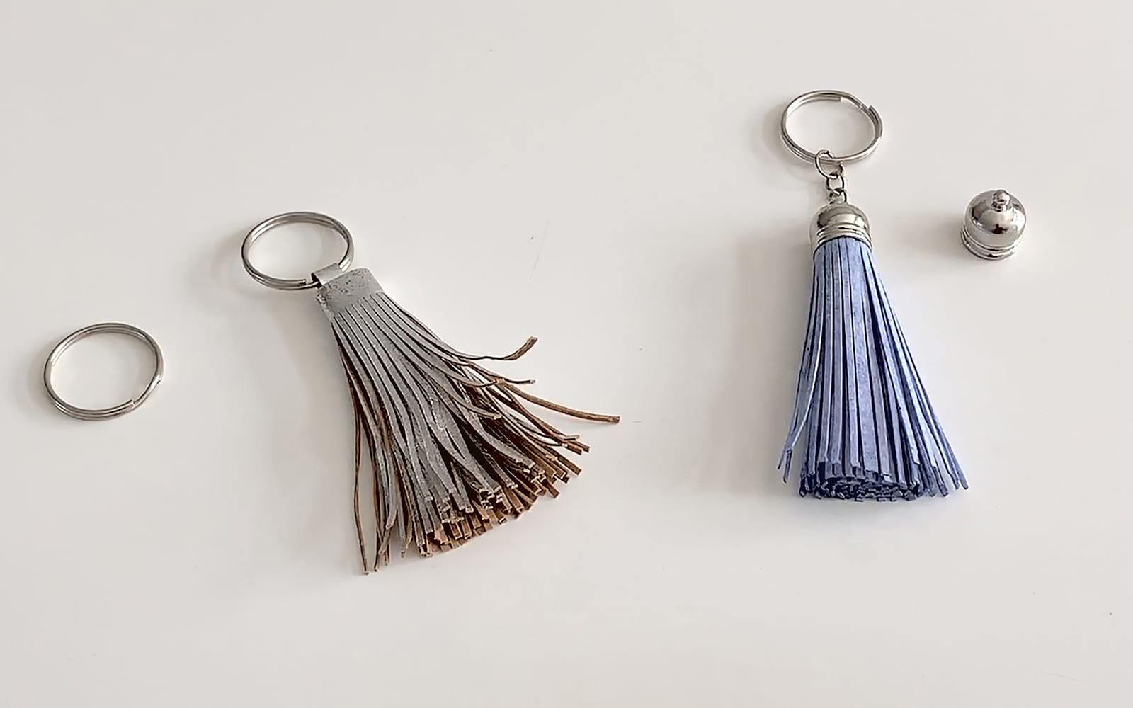 a silver and a blue tasselled key ring next to each other
