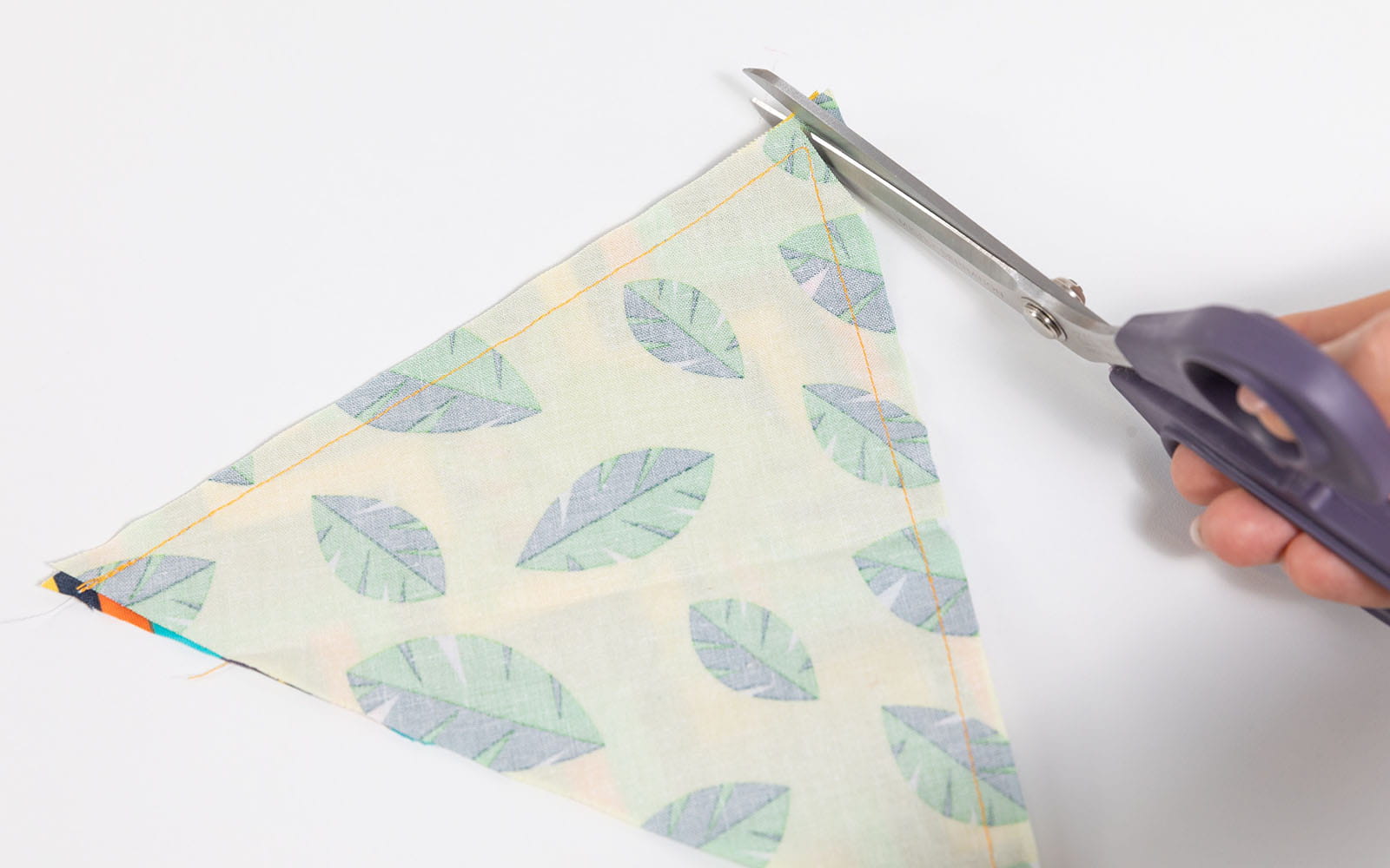 Hand scissors cutting point off bunting triangle