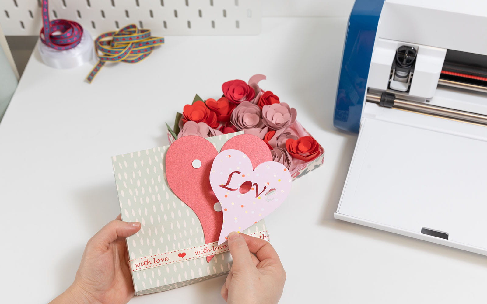 Hands sticking cut out heart with word love on to craft box lid