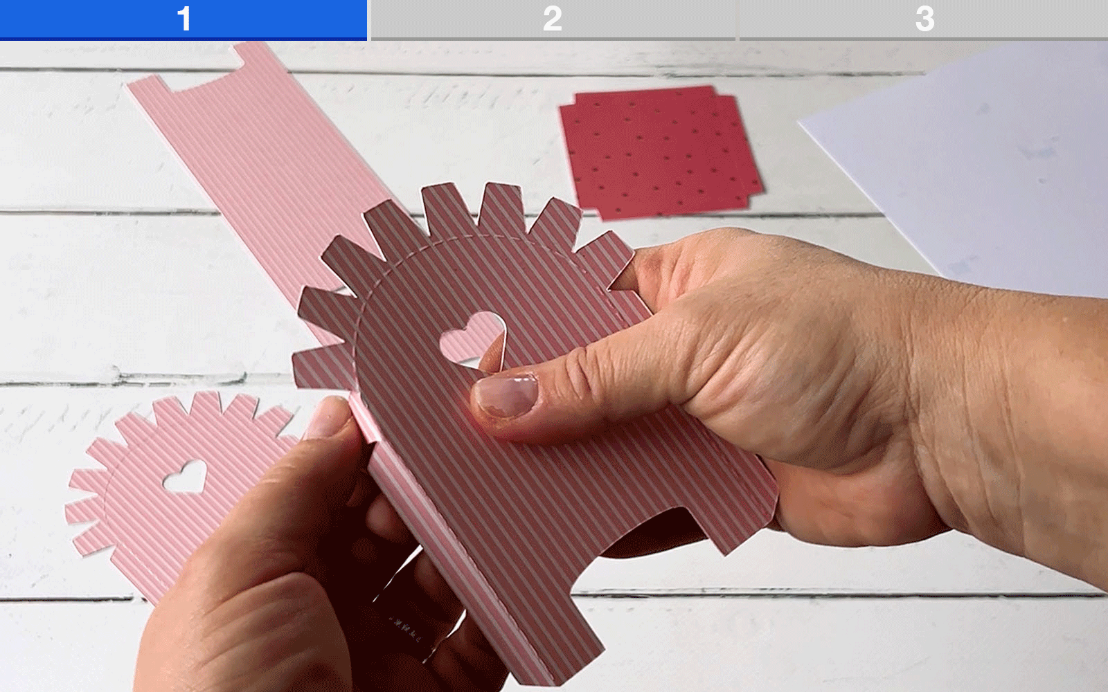 Hands folding pink card on white background