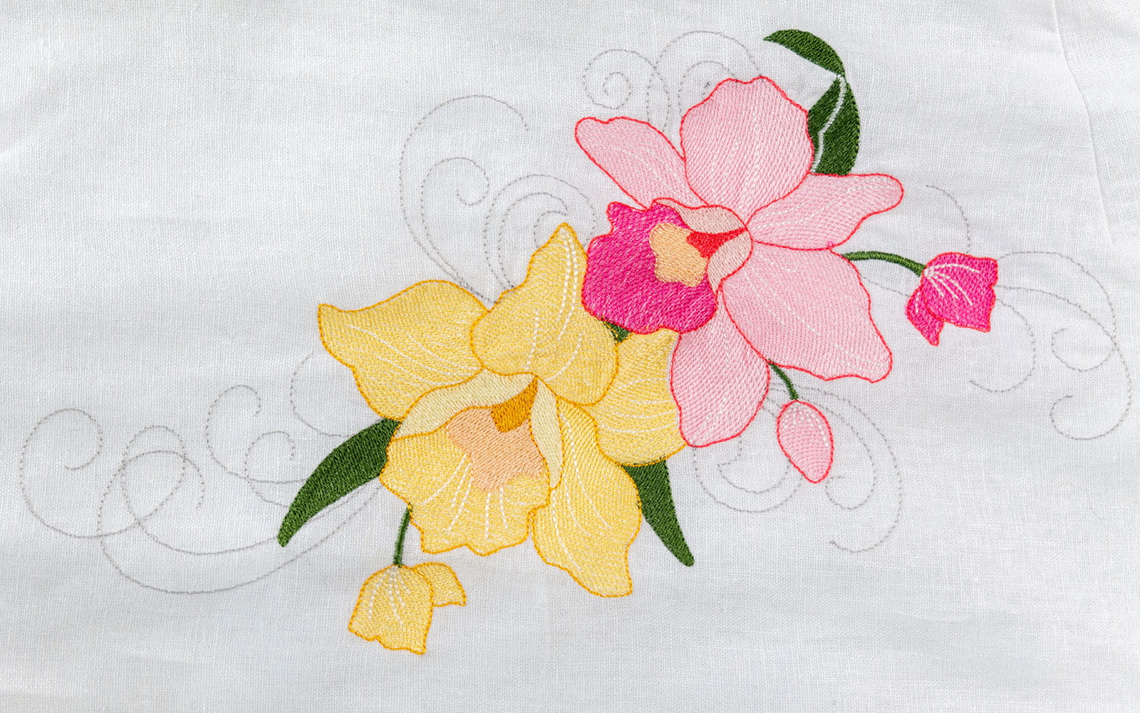 close up of pink and yellow embroidered orchid on breast of white dress