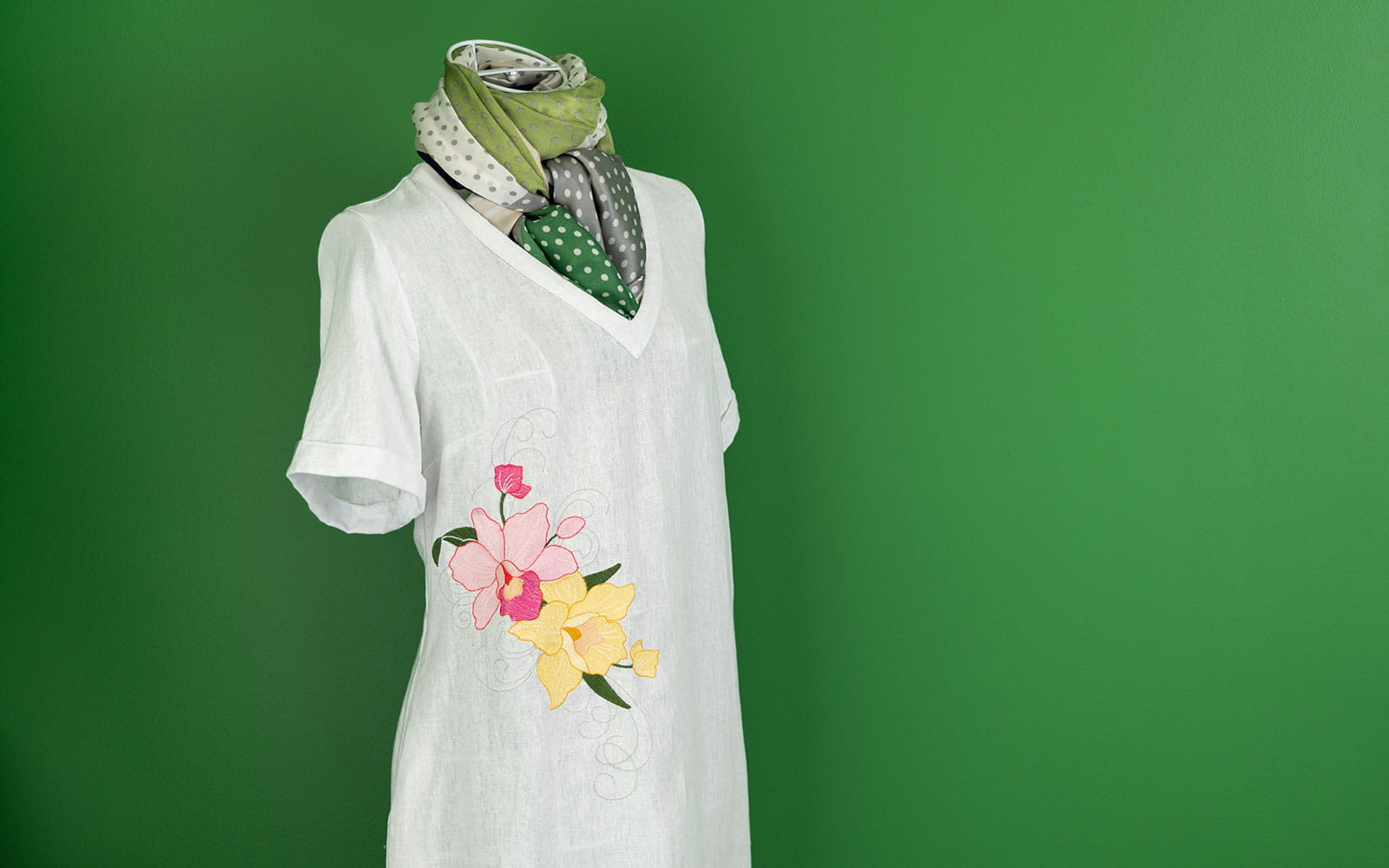 linen dress with pink and yellow orchid embroidery against dark green wall