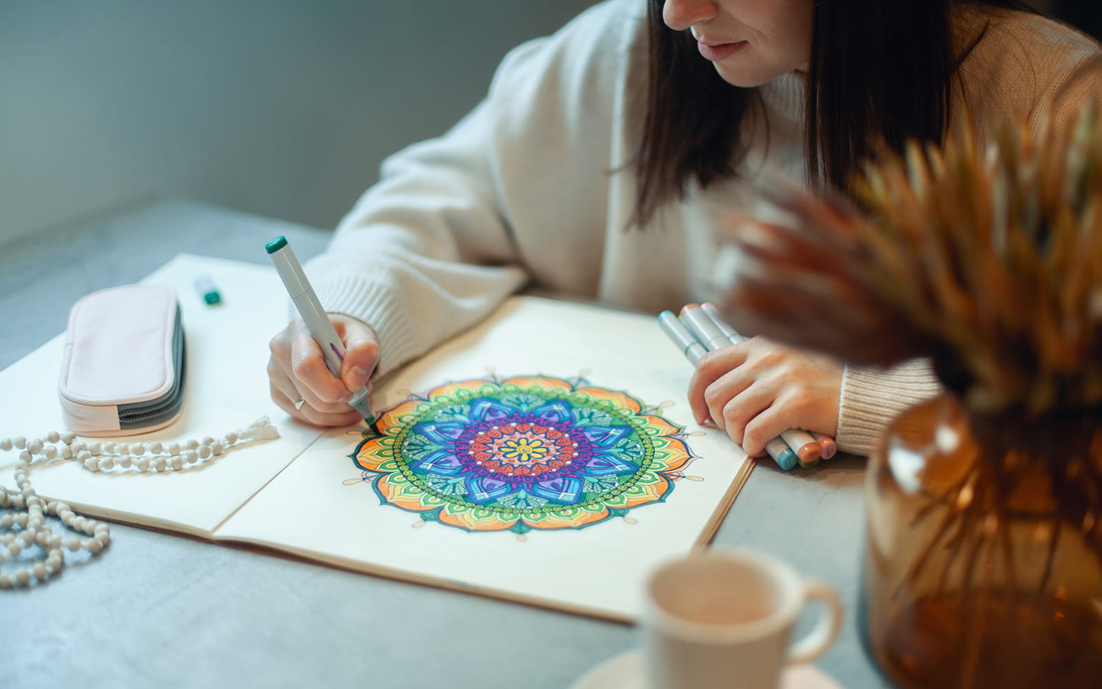Vrouw kleurt in mandala tekening in regenboogkleuren