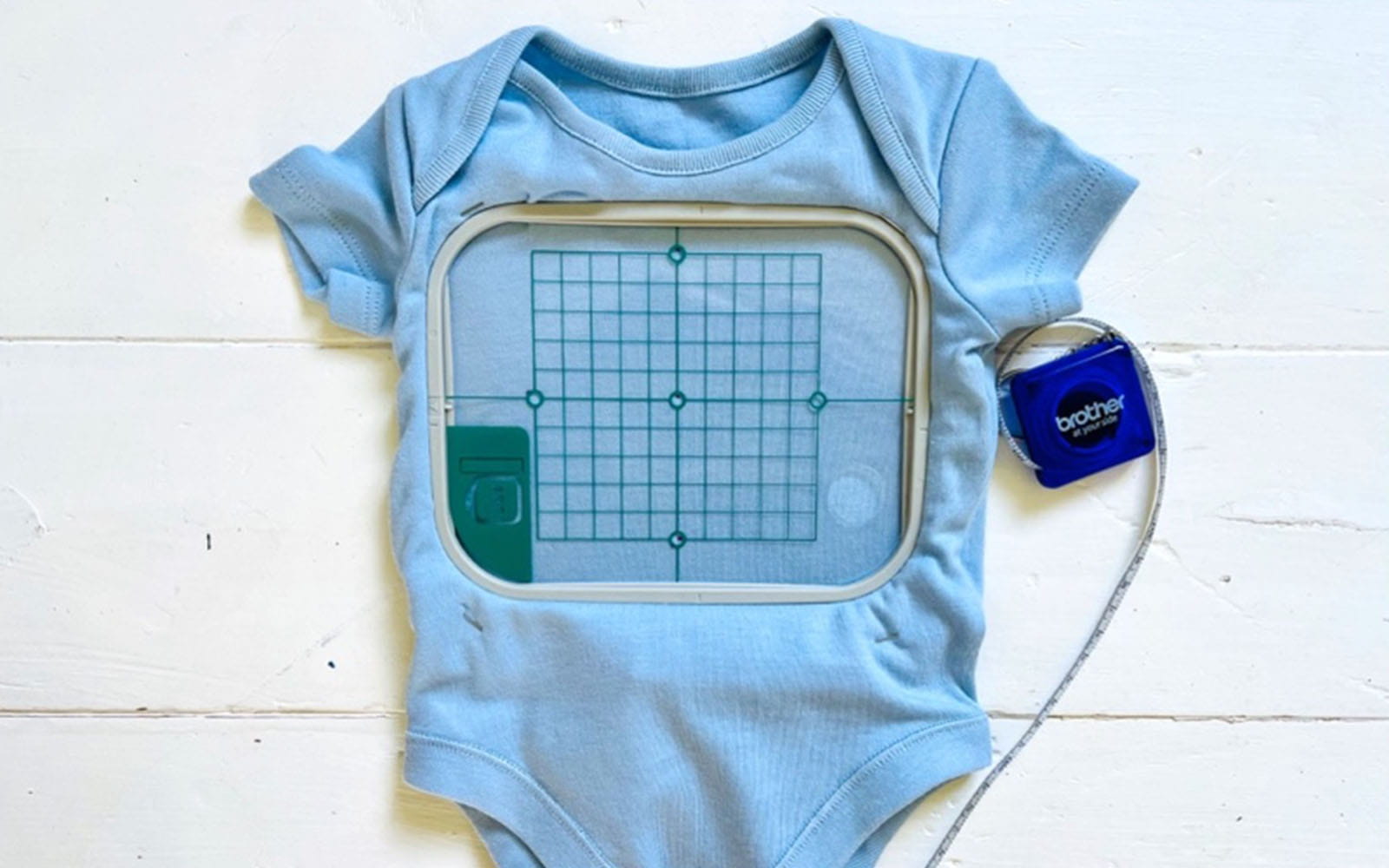 Blue babygrow hooped into Brother machine embroidery hoop