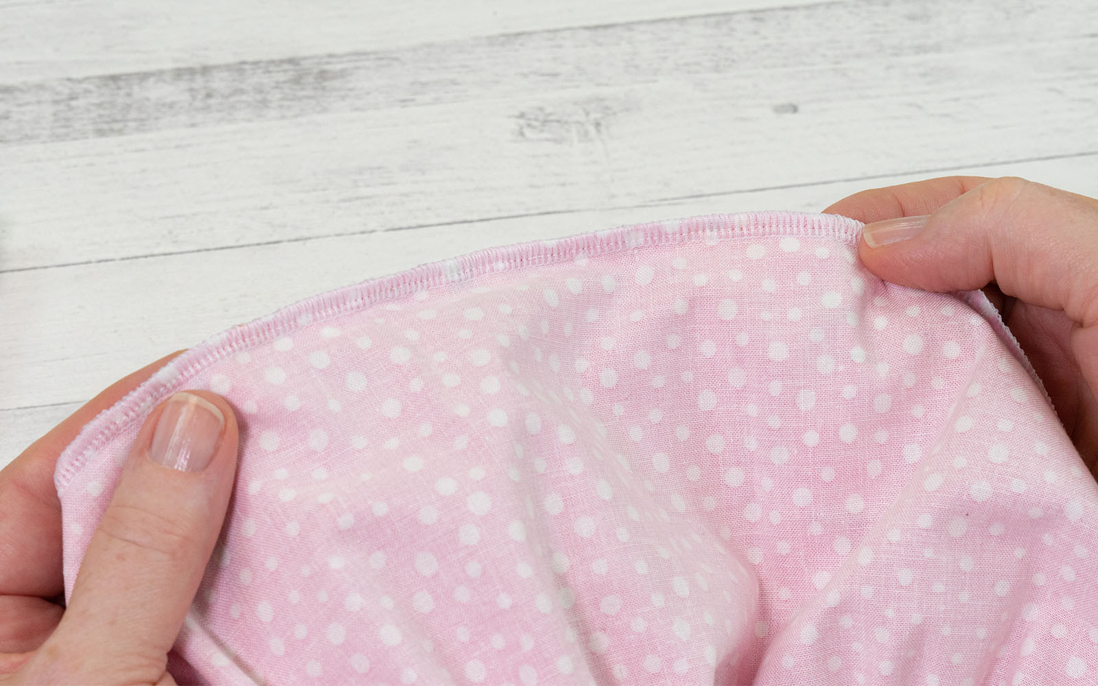 Pink fabric held in hands on white background