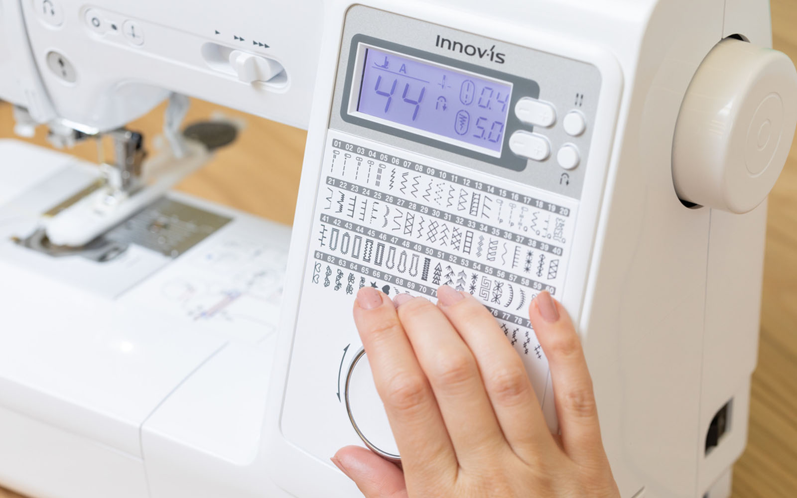 Hand choosing buttonhole stitch on dial on Brother sewing machine