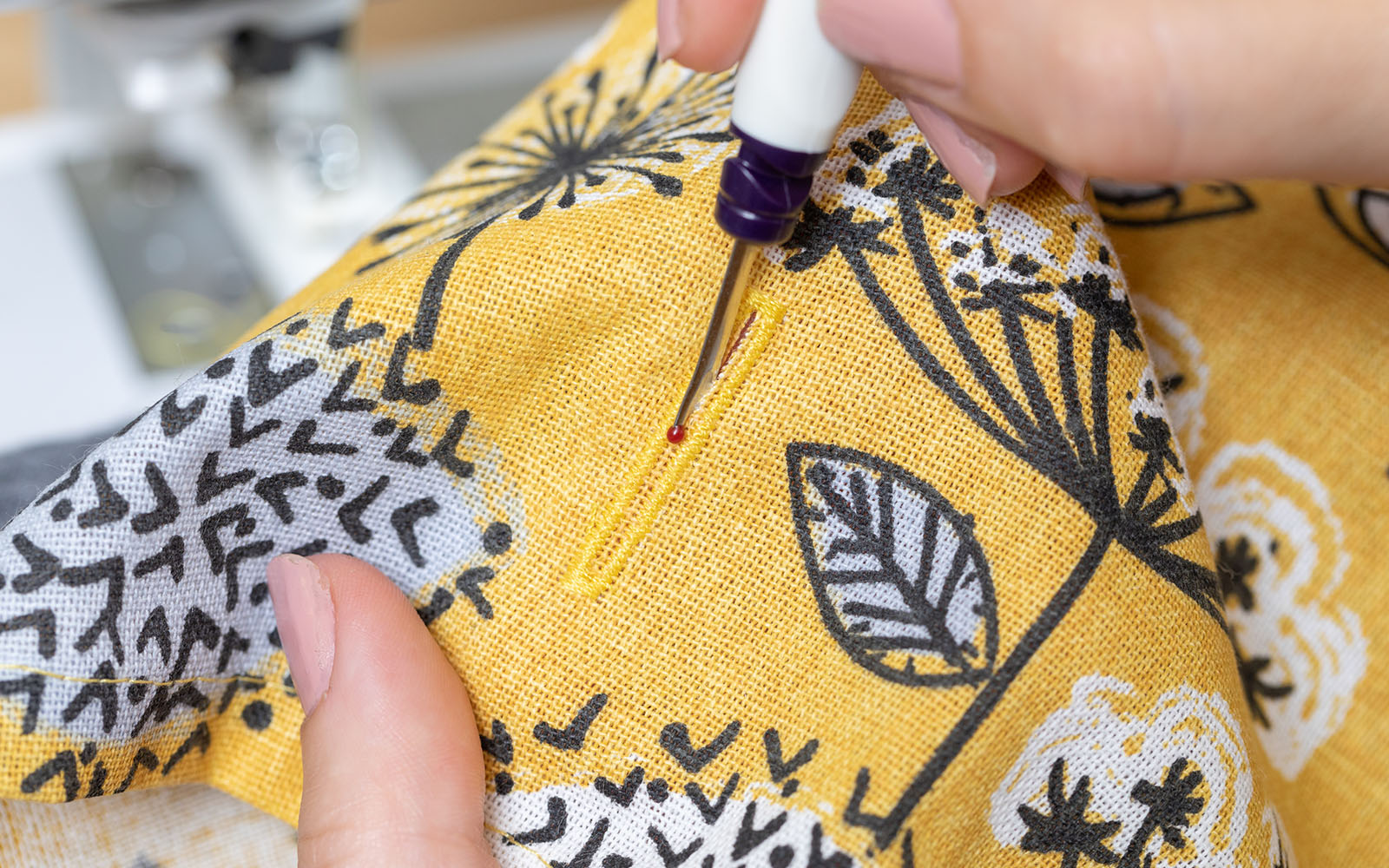 Seam ripper opening buttonhole in yellow material