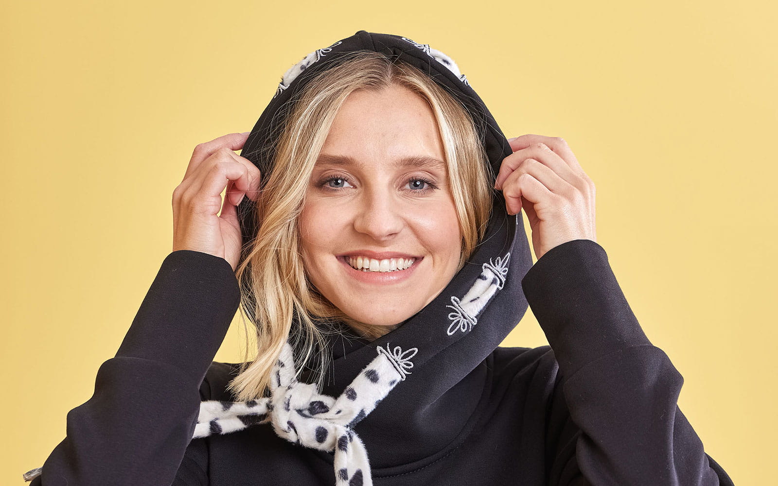 blonde woman wearing hoodie with decorative embroidered buttonholes
