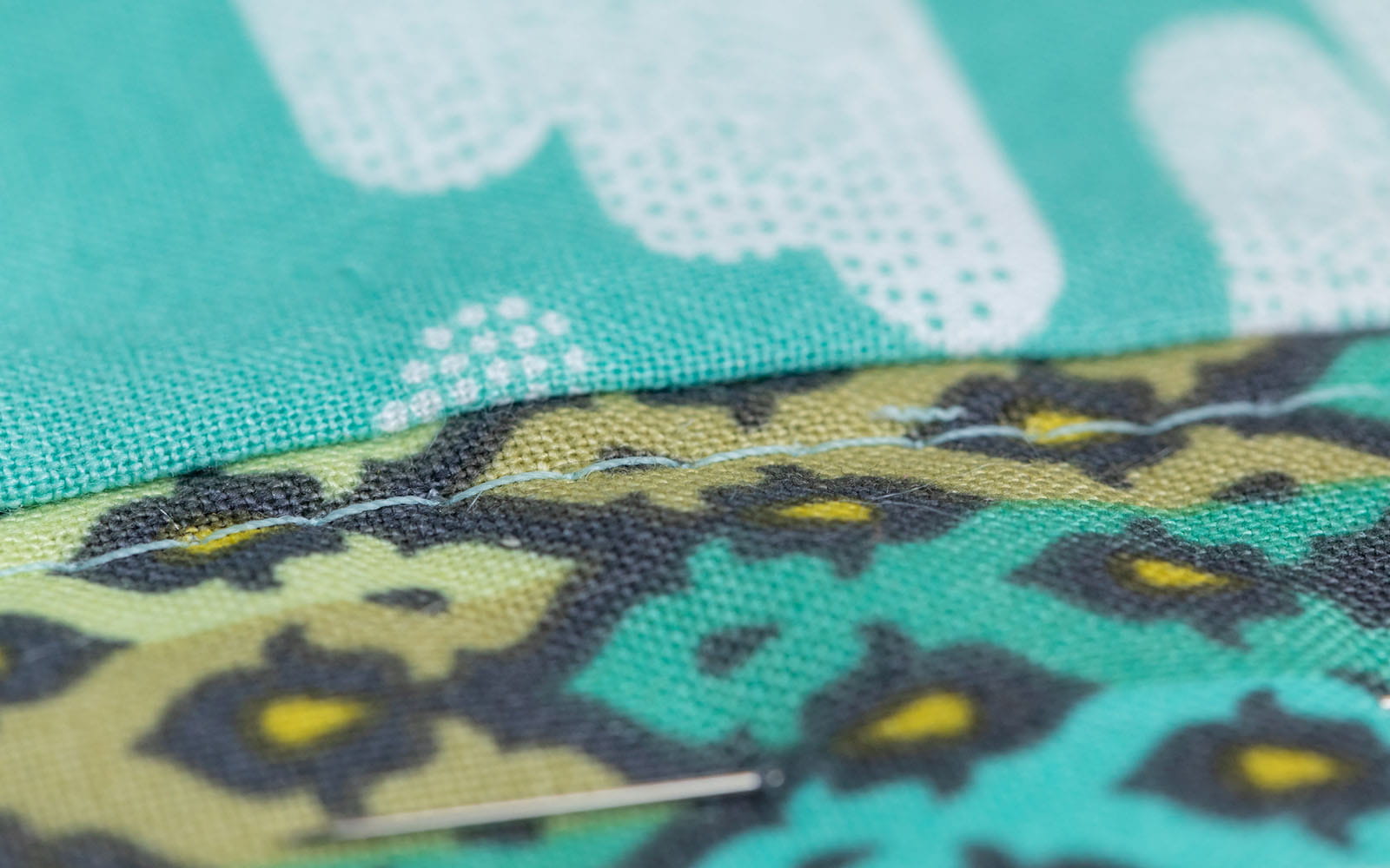 close up sewn top stitch on green patterned fabric