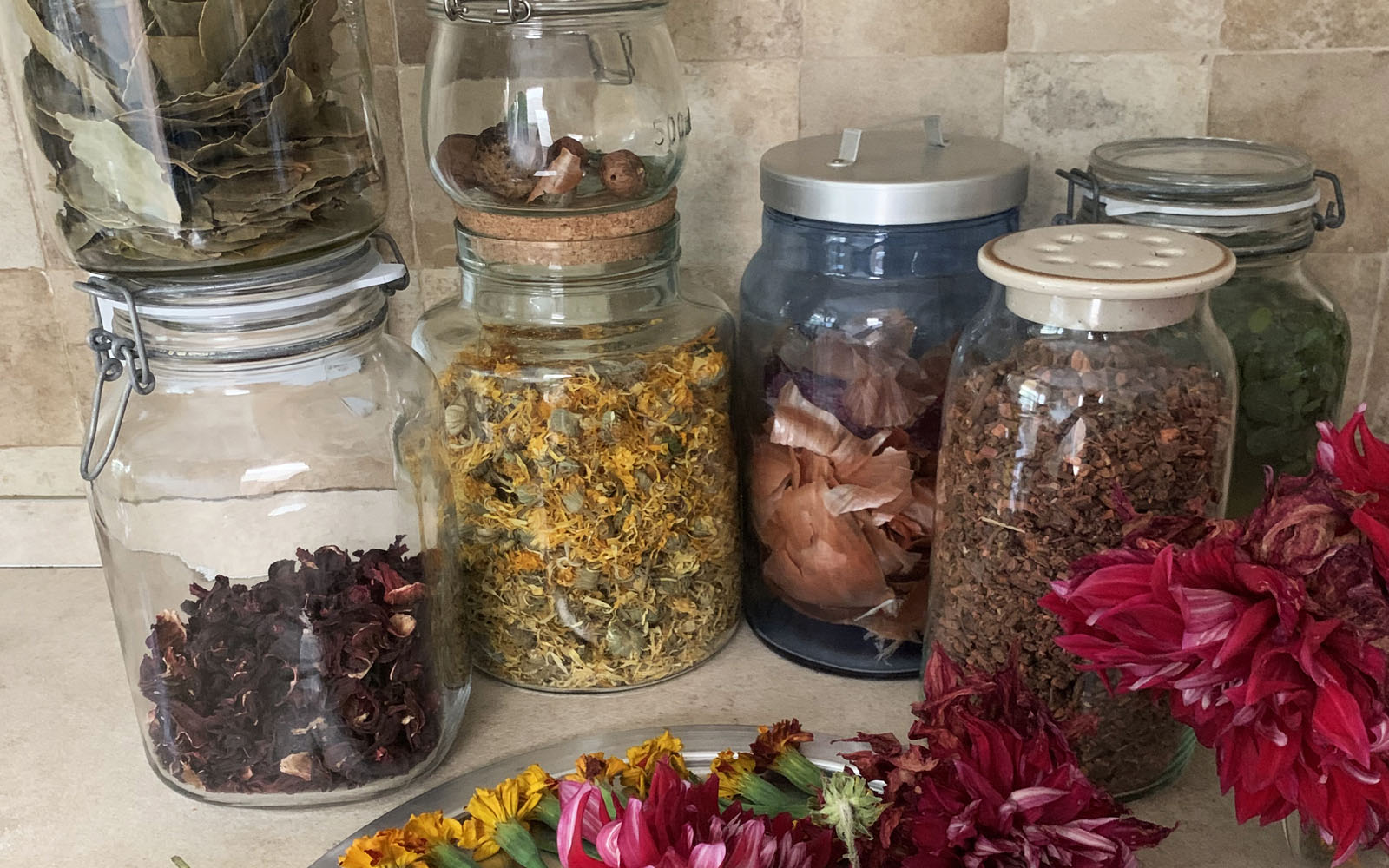 five glass jars on worktop filled with dried flowers