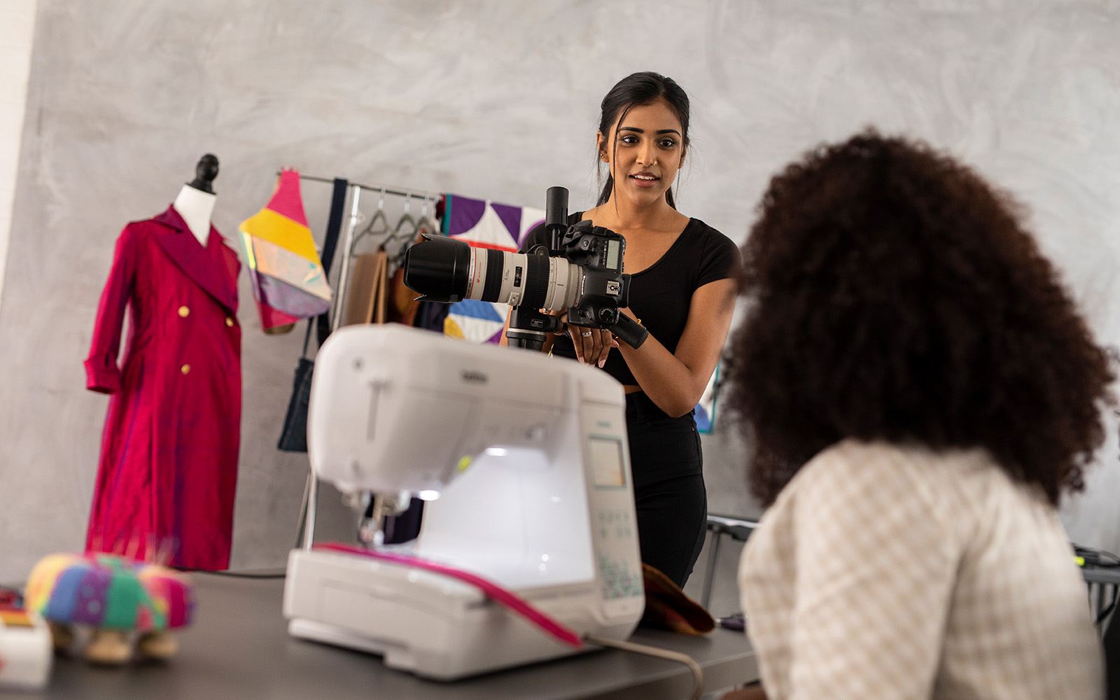 woman sitting at sewing machine talking to photographer