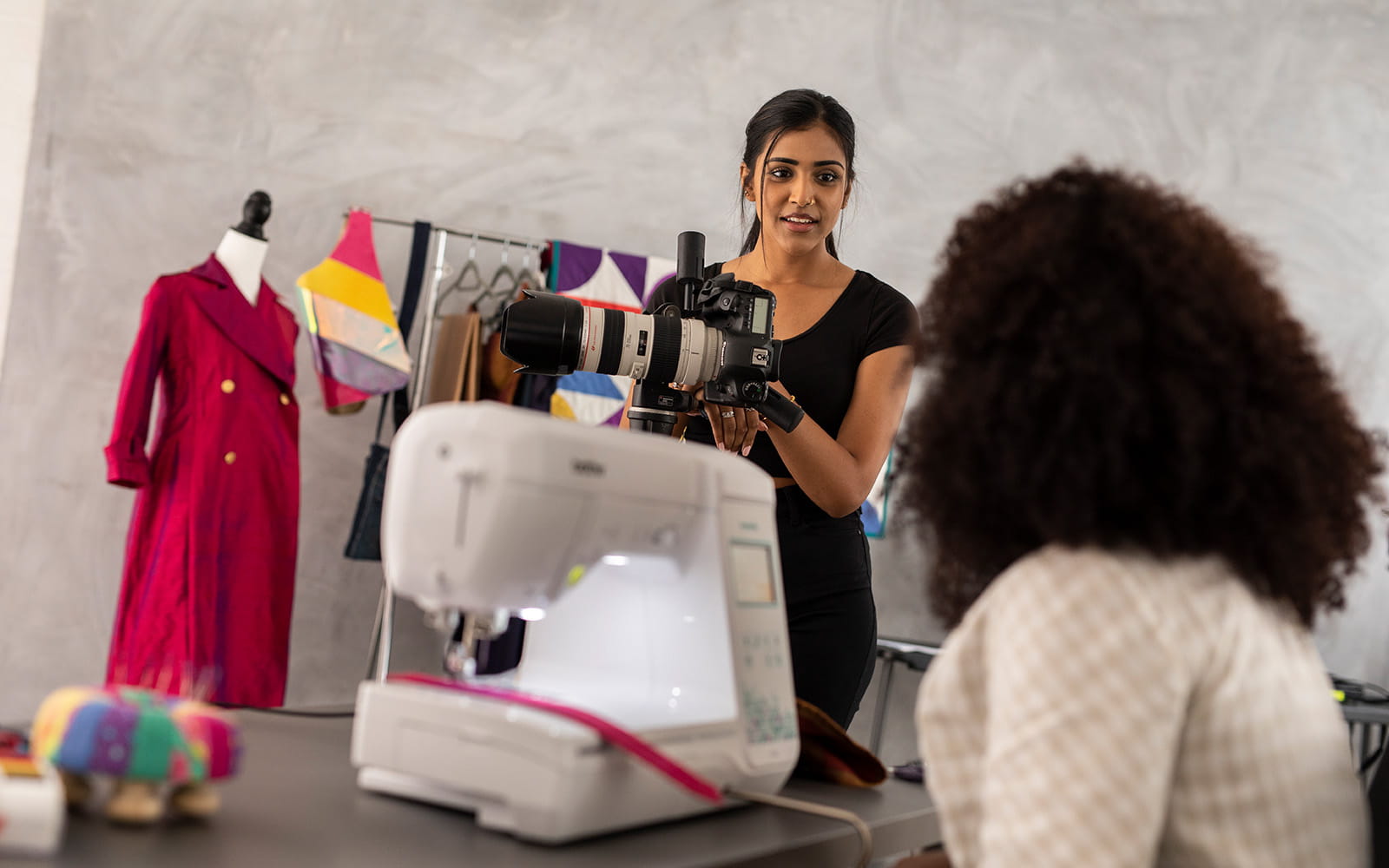 Vrouw aan haar naaimachine in gesprek met een fotograaf