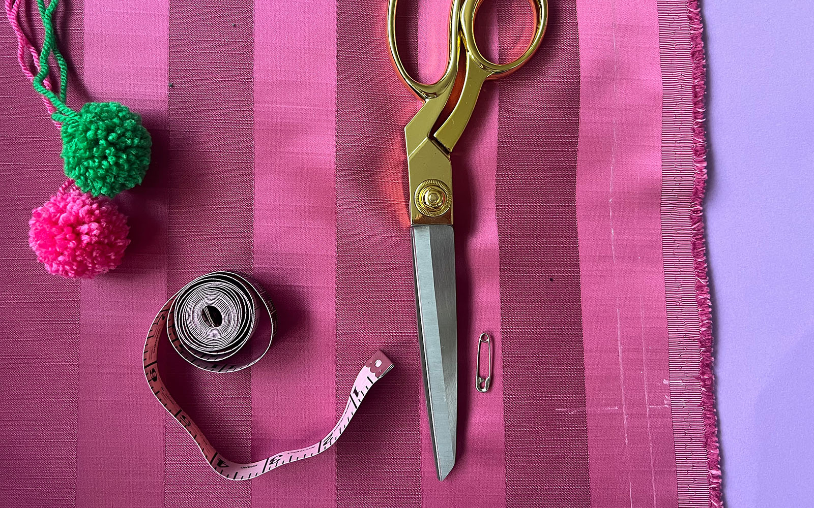 scissors, measuring tape, pompom, pink fabric