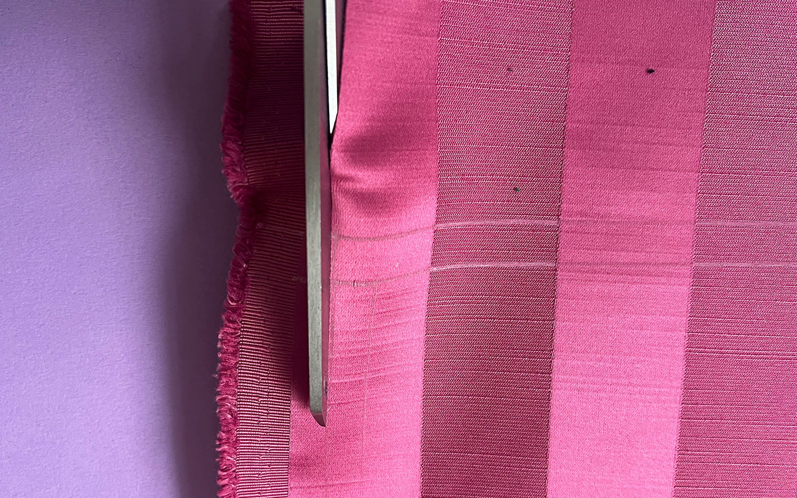 close up scissors cutting pink striped fabric