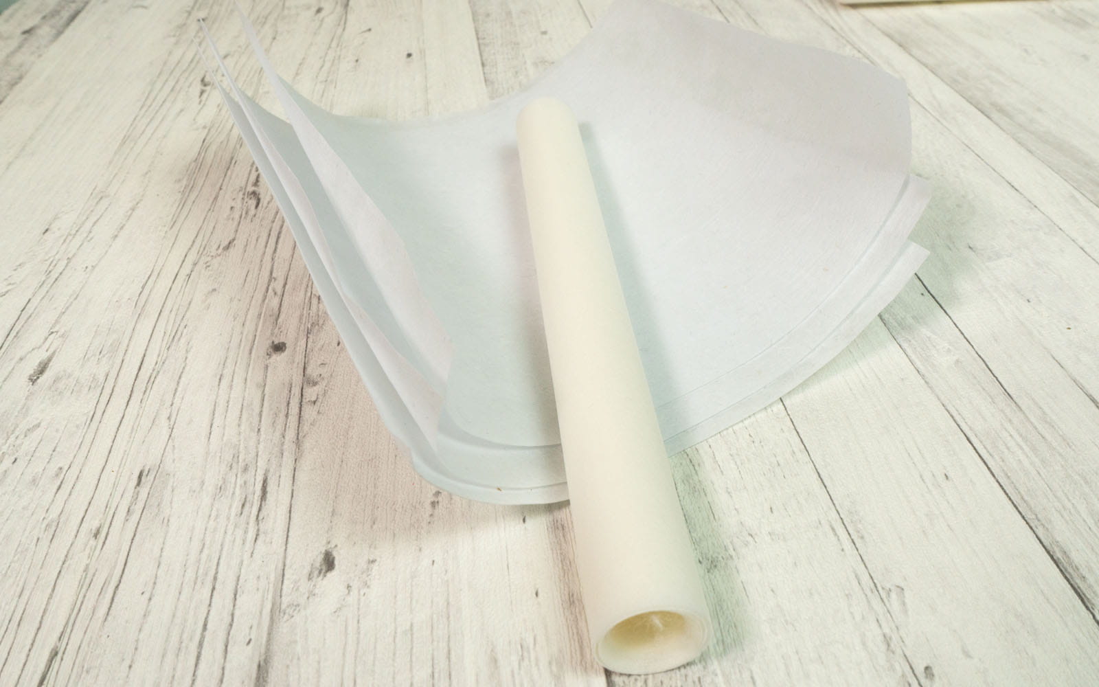 Multiple white sheets and a roll of stabiliser on wooden background