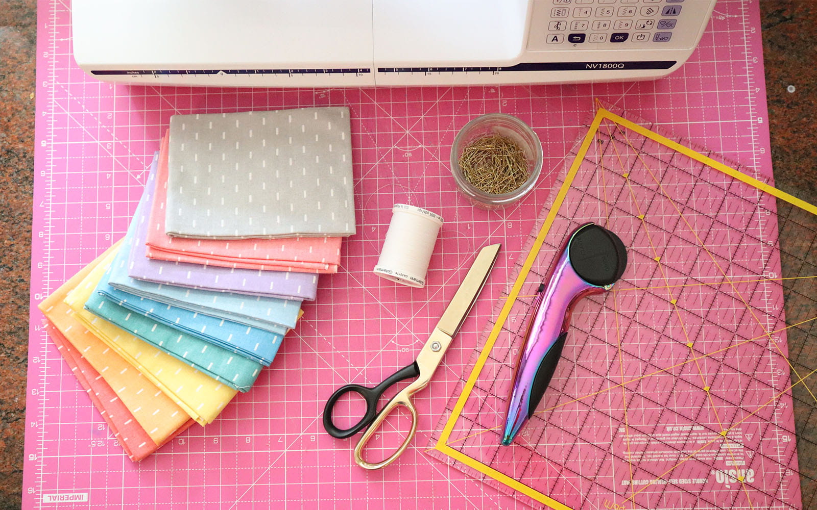 Different coloured fabrics and tools on pink cutting mat