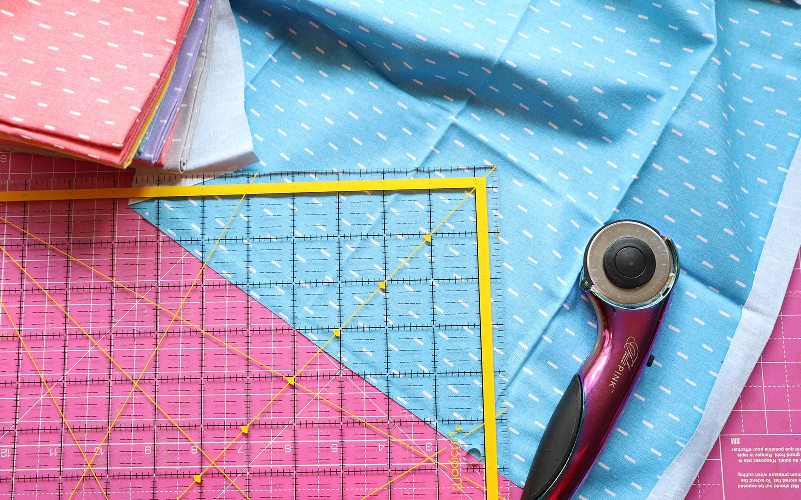 Quilt ruler and rotary cutter on blue fabric