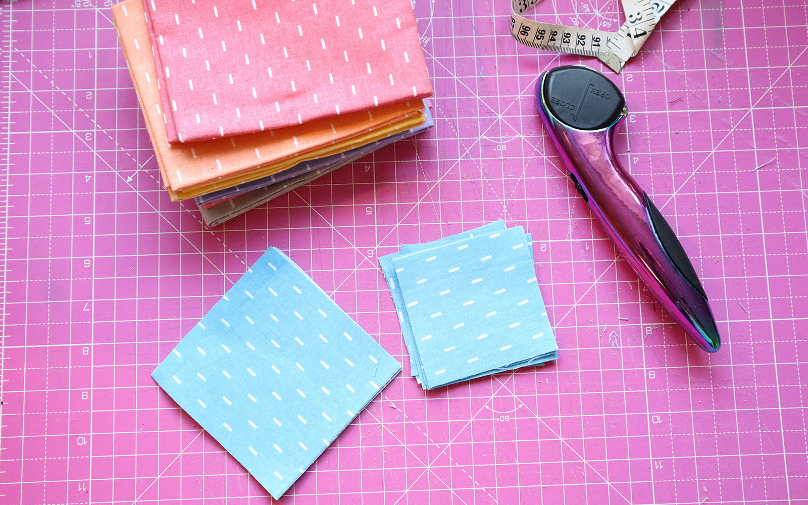 Blue fabric squares in 2 sizes on pink cutting mat