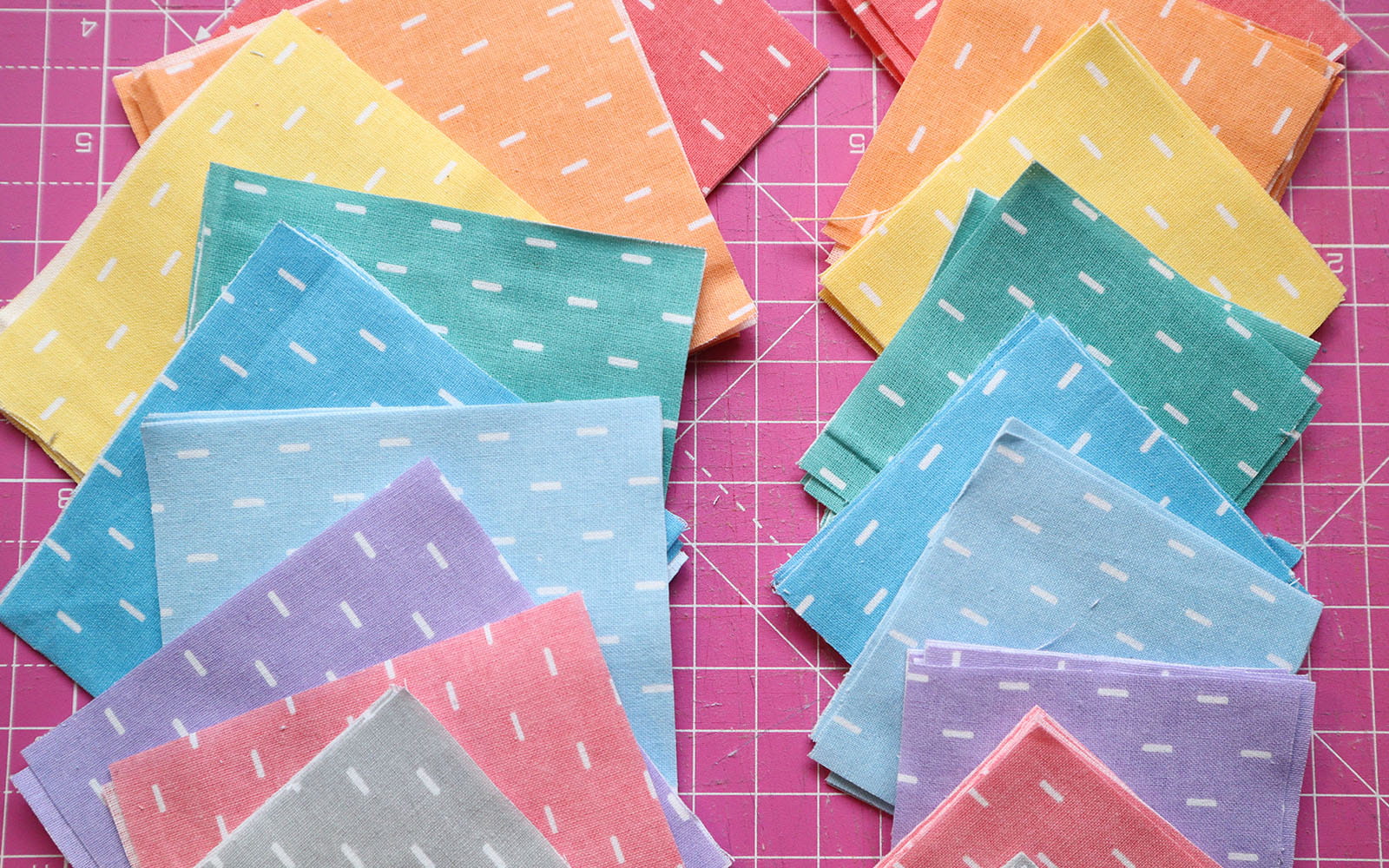 Stacks of fabric squares in different pastel colours and sizes