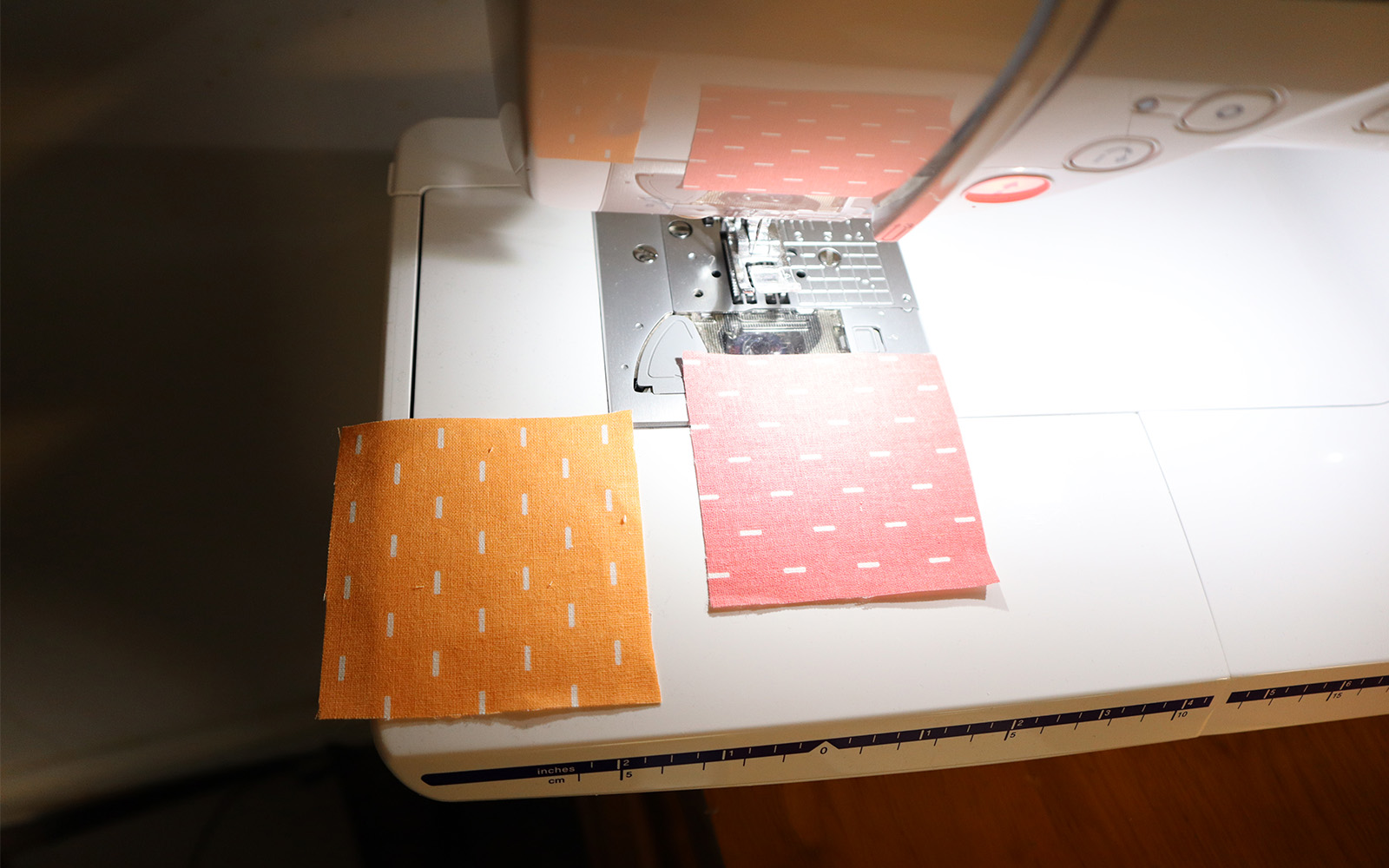 Orange and pink fabric squares on white sewing machine