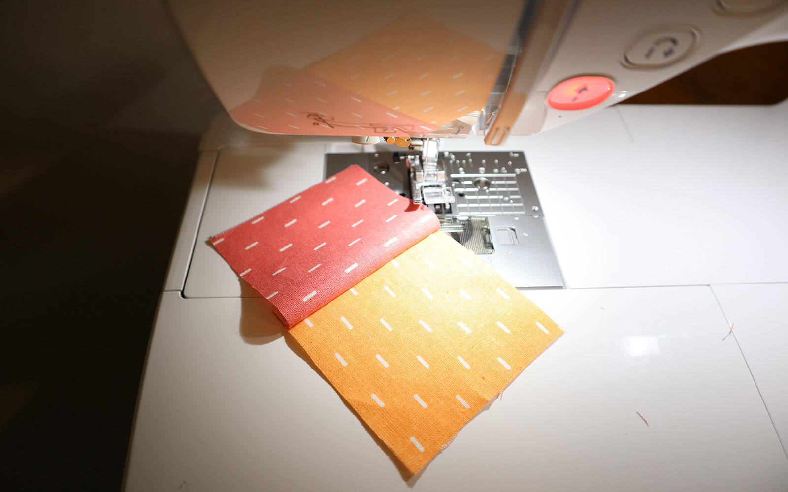 Orange and pink squares sewn together open on white sewing machine