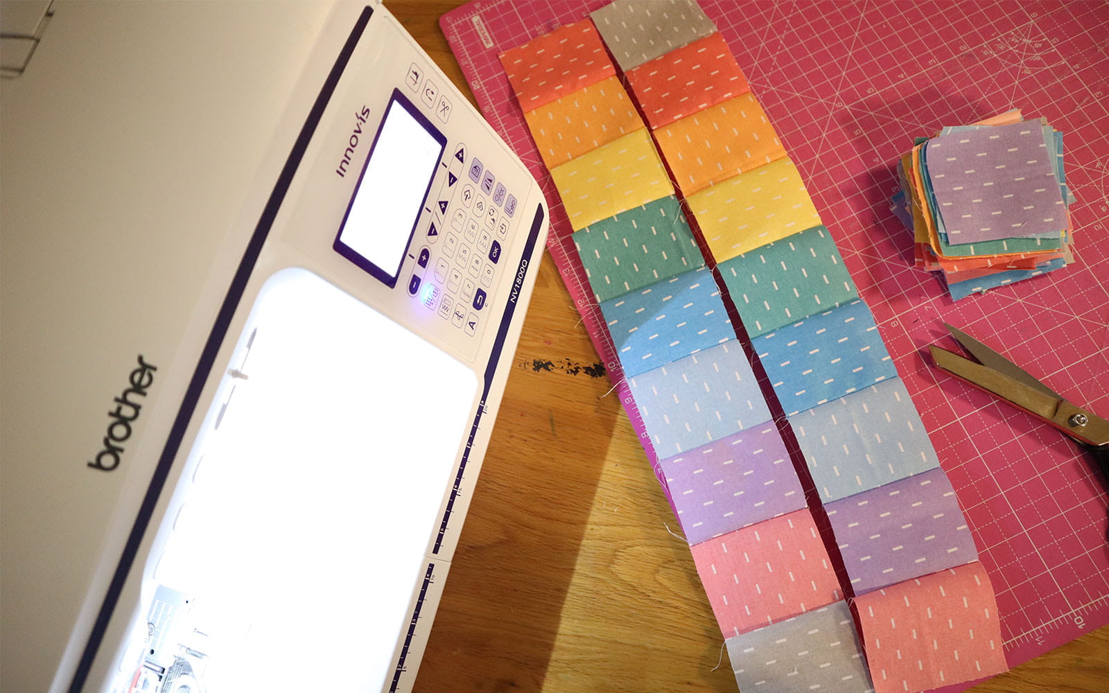 Two strips of alternating coloured fabric squares on pink cutting mat