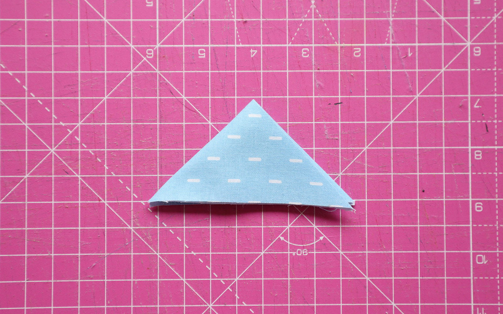 Double folded triangle shape fabric on pink cutting mat