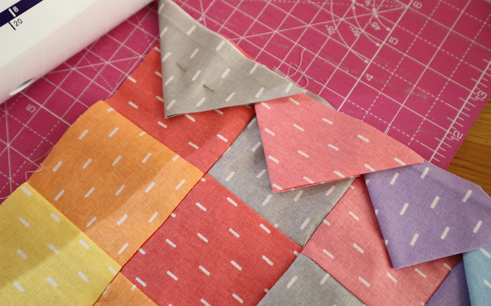Fabric triangles pinned to edge of square pieced fabric
