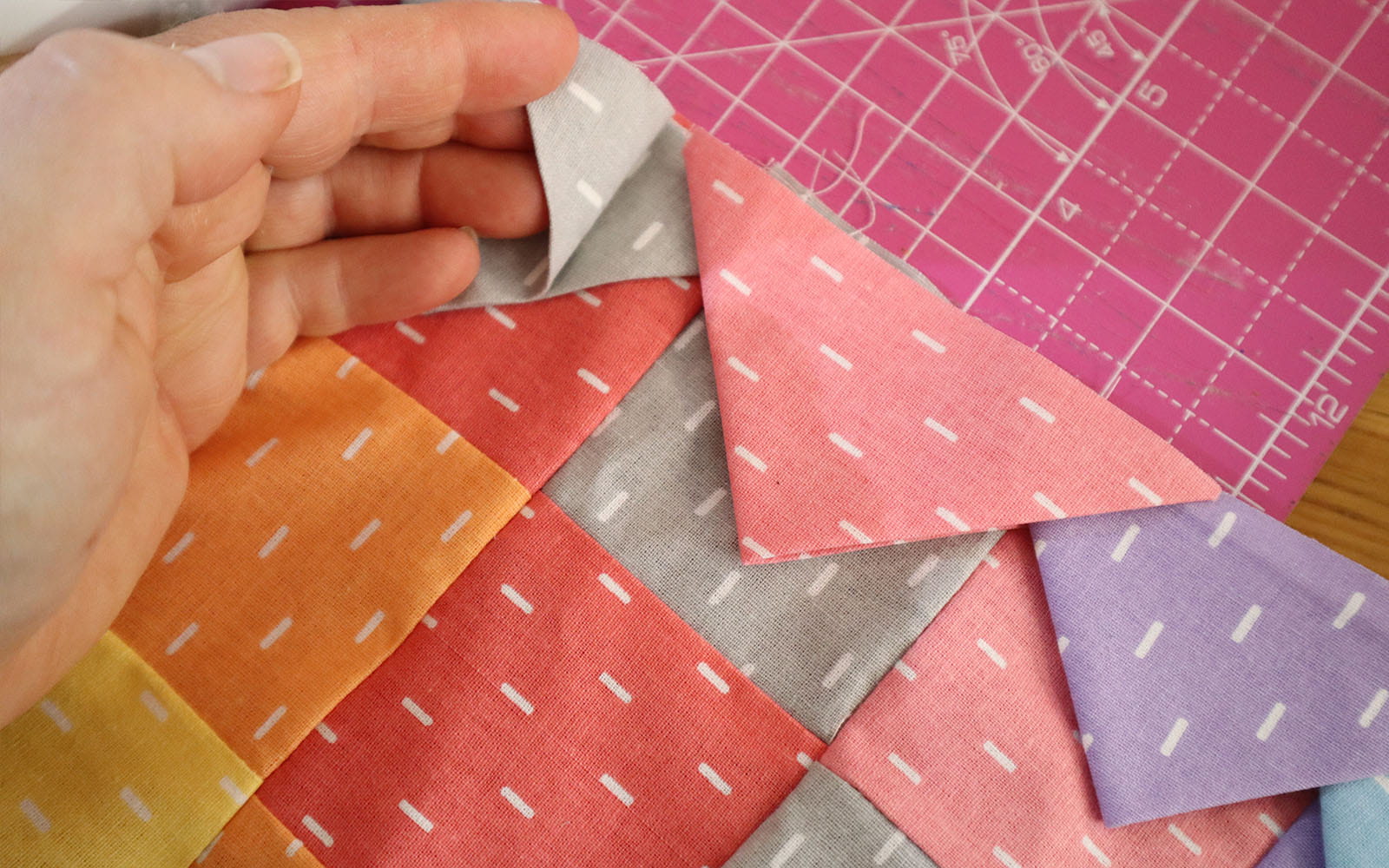 Hand lifting corner of grey fabric triangle to show placement