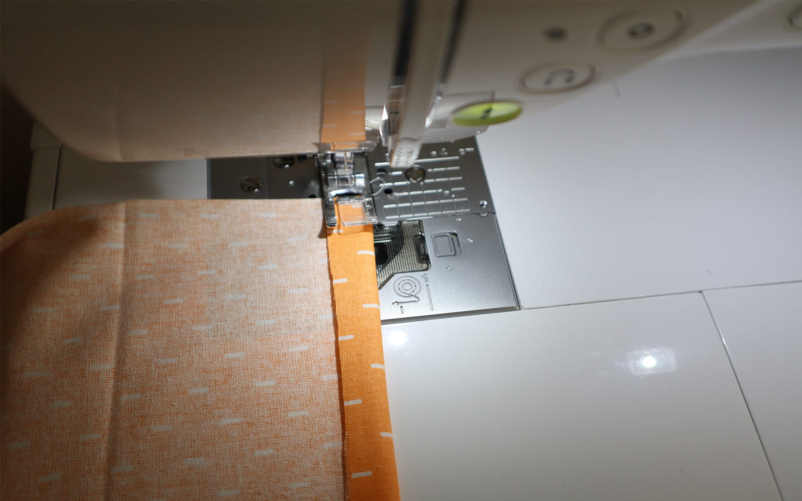 Folded orange fabric being sewn in sewing machine