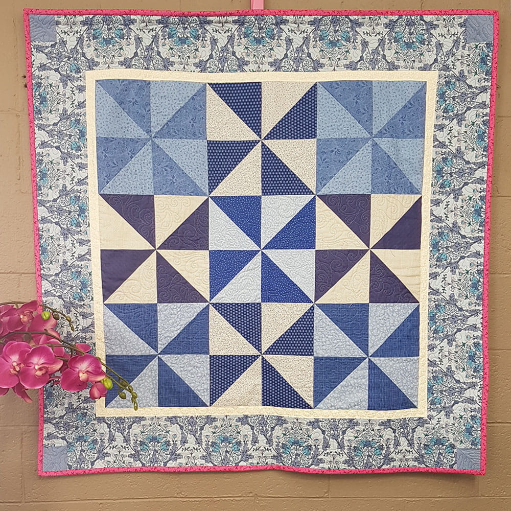 Blue quilt on wall with pink flowers