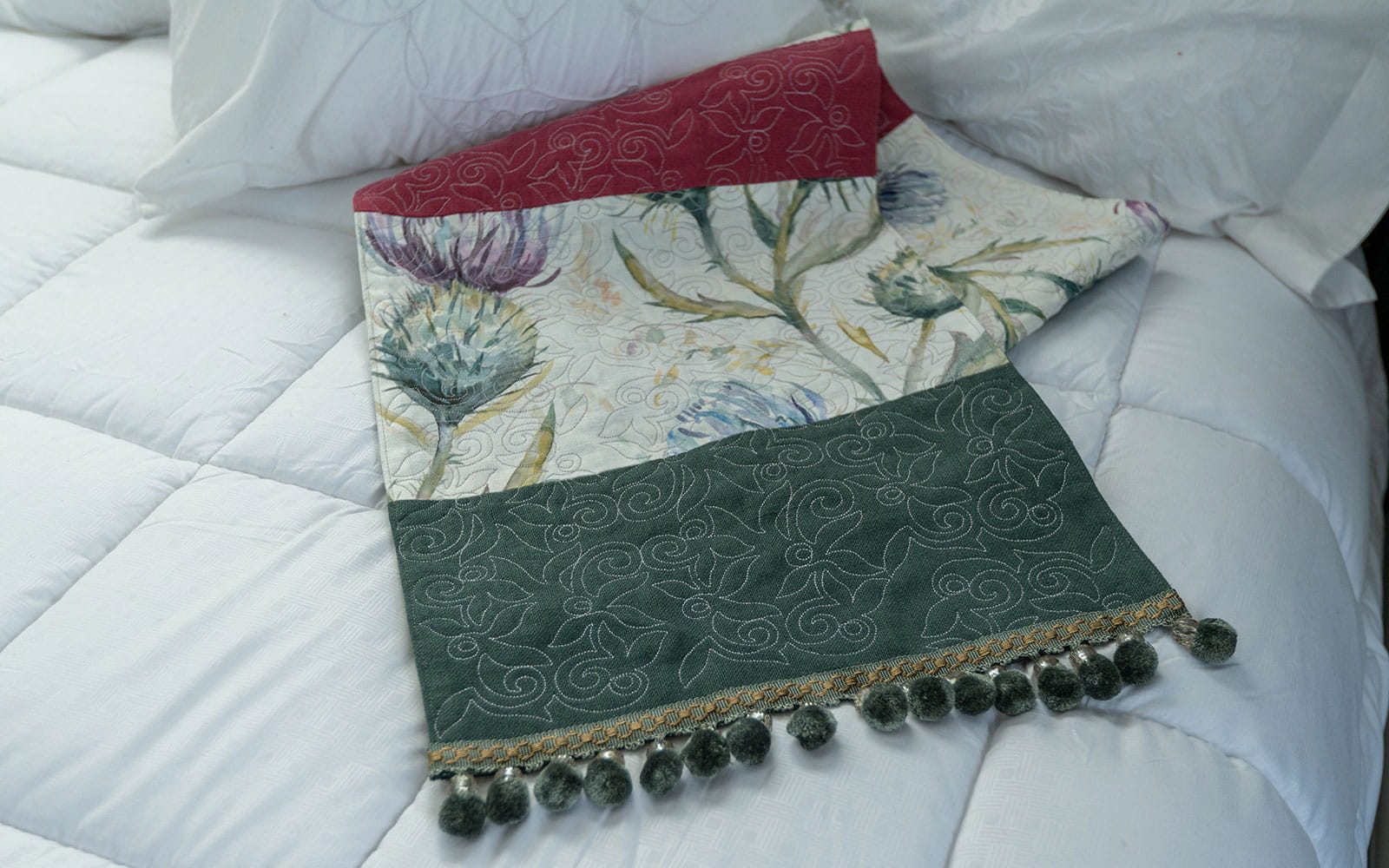 Close up of swirly embroidering on red and green bed runner place