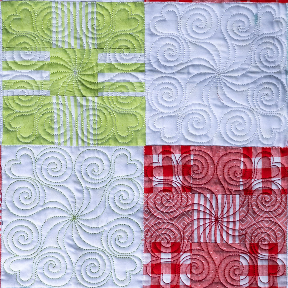 red, white and green quilt squares with swirly embroidery stitched on