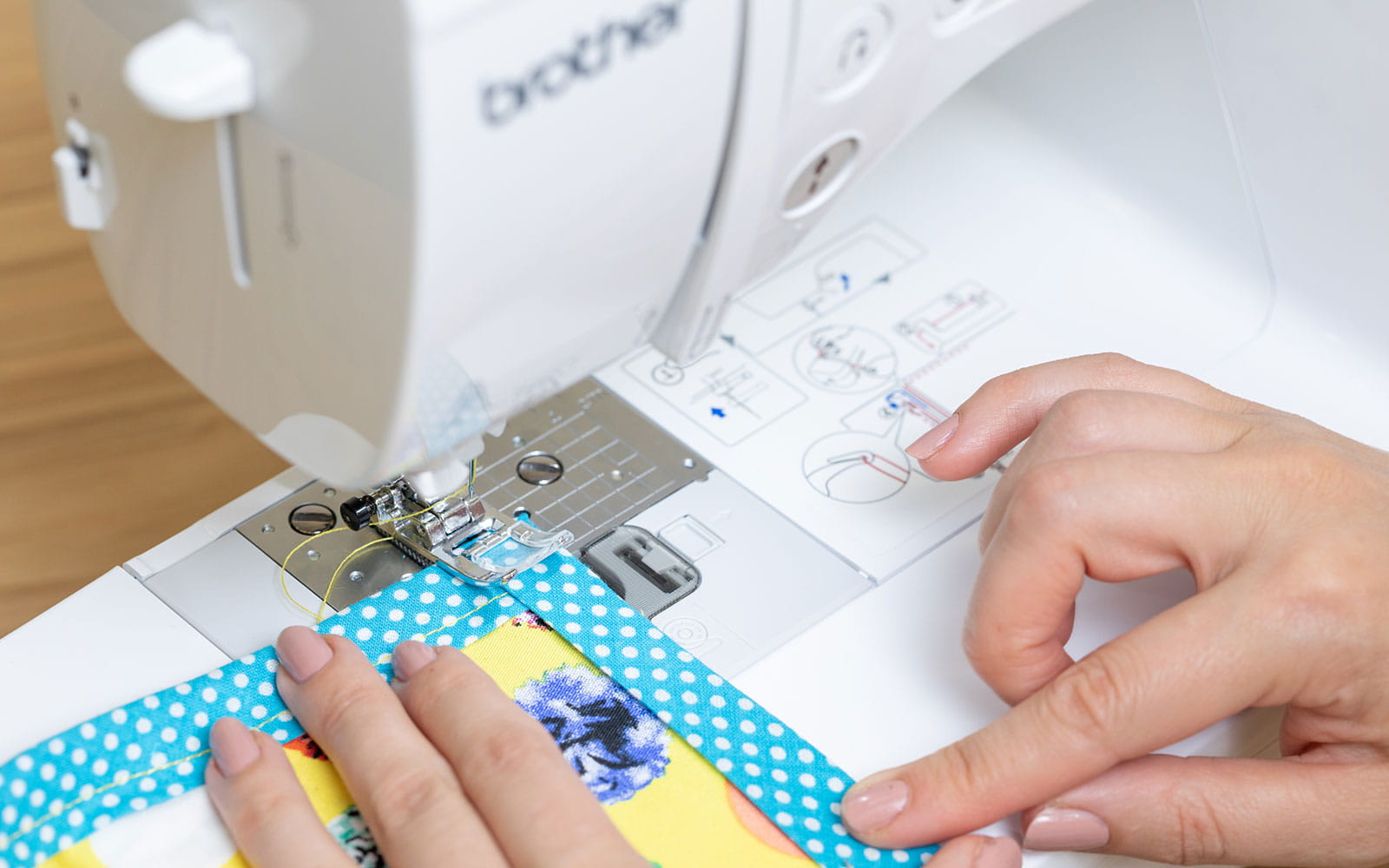 woman sewing yellow apron with blue edging on sewing machine