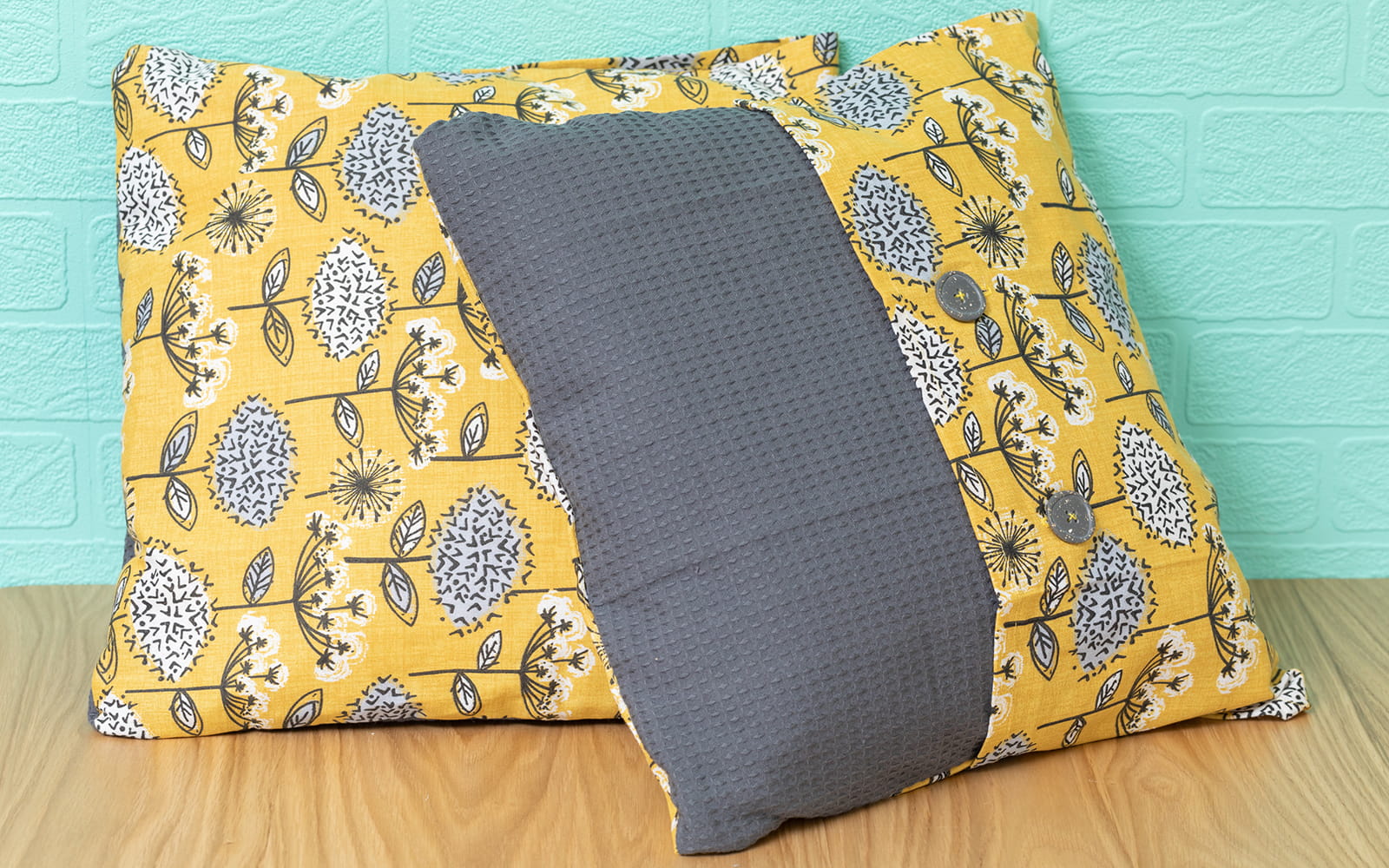 Grey and yellow tea towel cushions turquoise background