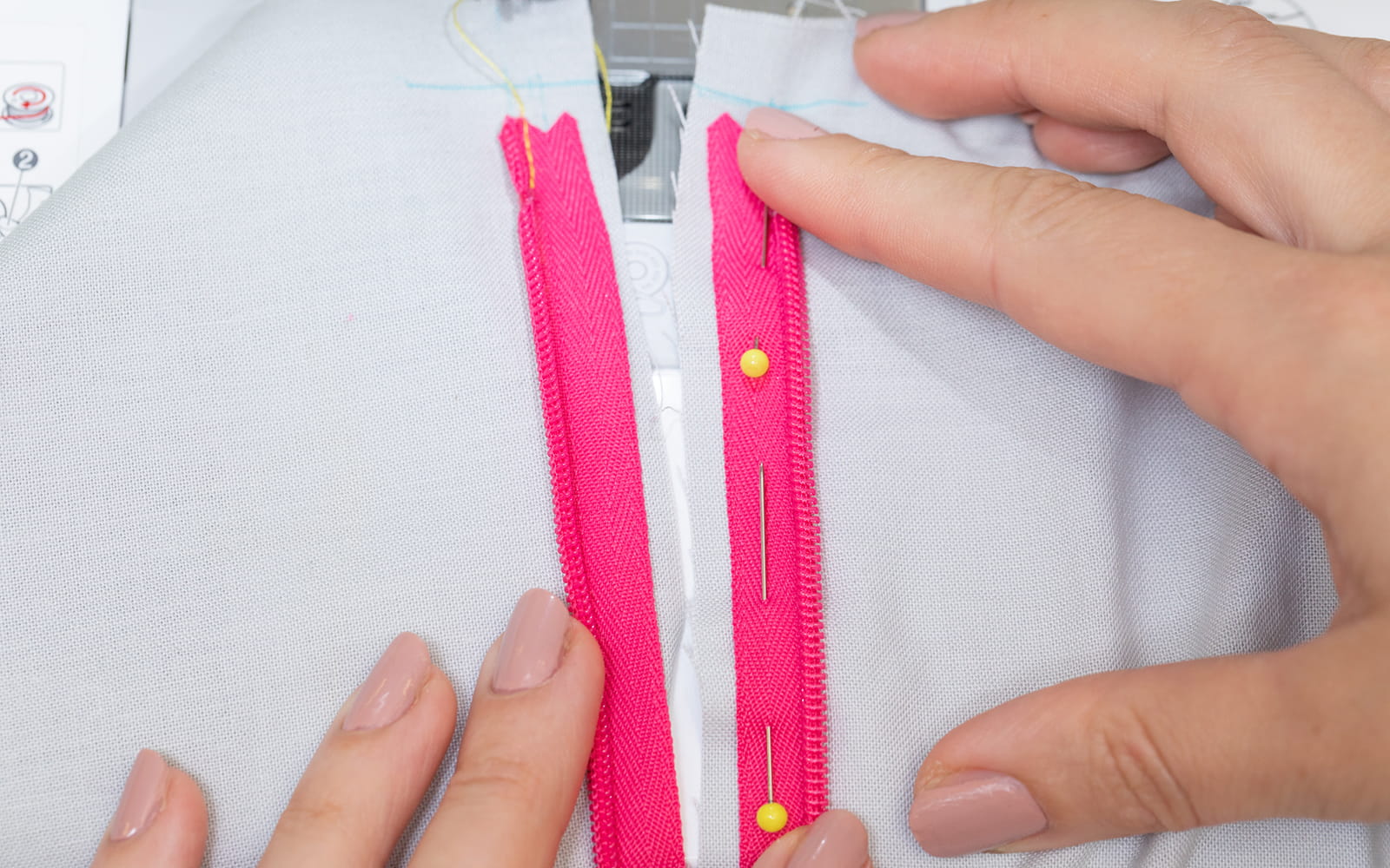 Hands pinning pink concealed zip in place