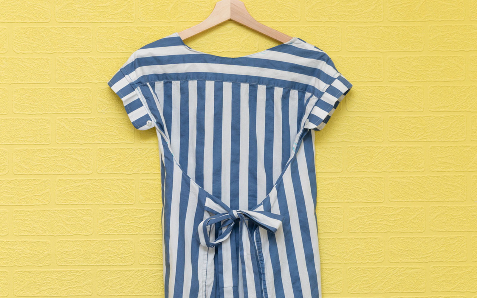 Blue and white striped top against yellow wall
