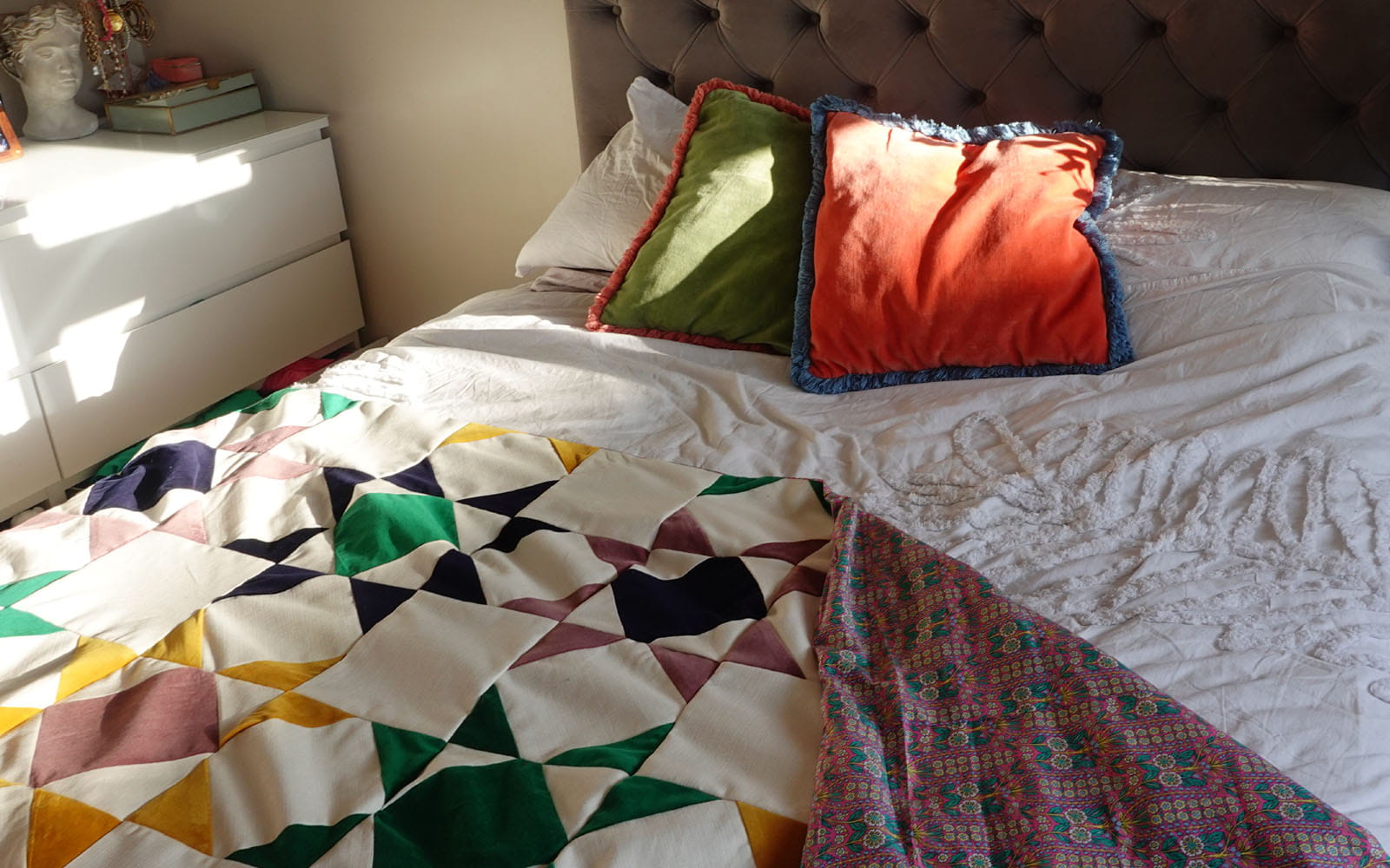 Geometric quilt styled on white bed