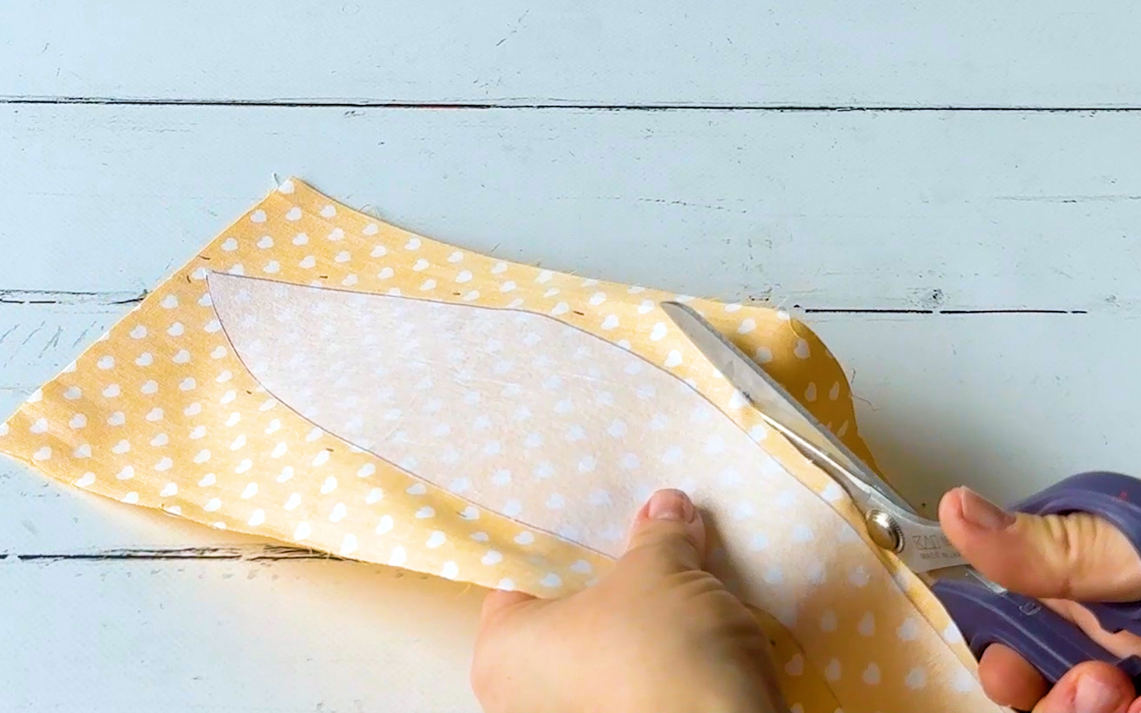 Scissors cutting white and yellow polka dot fabric