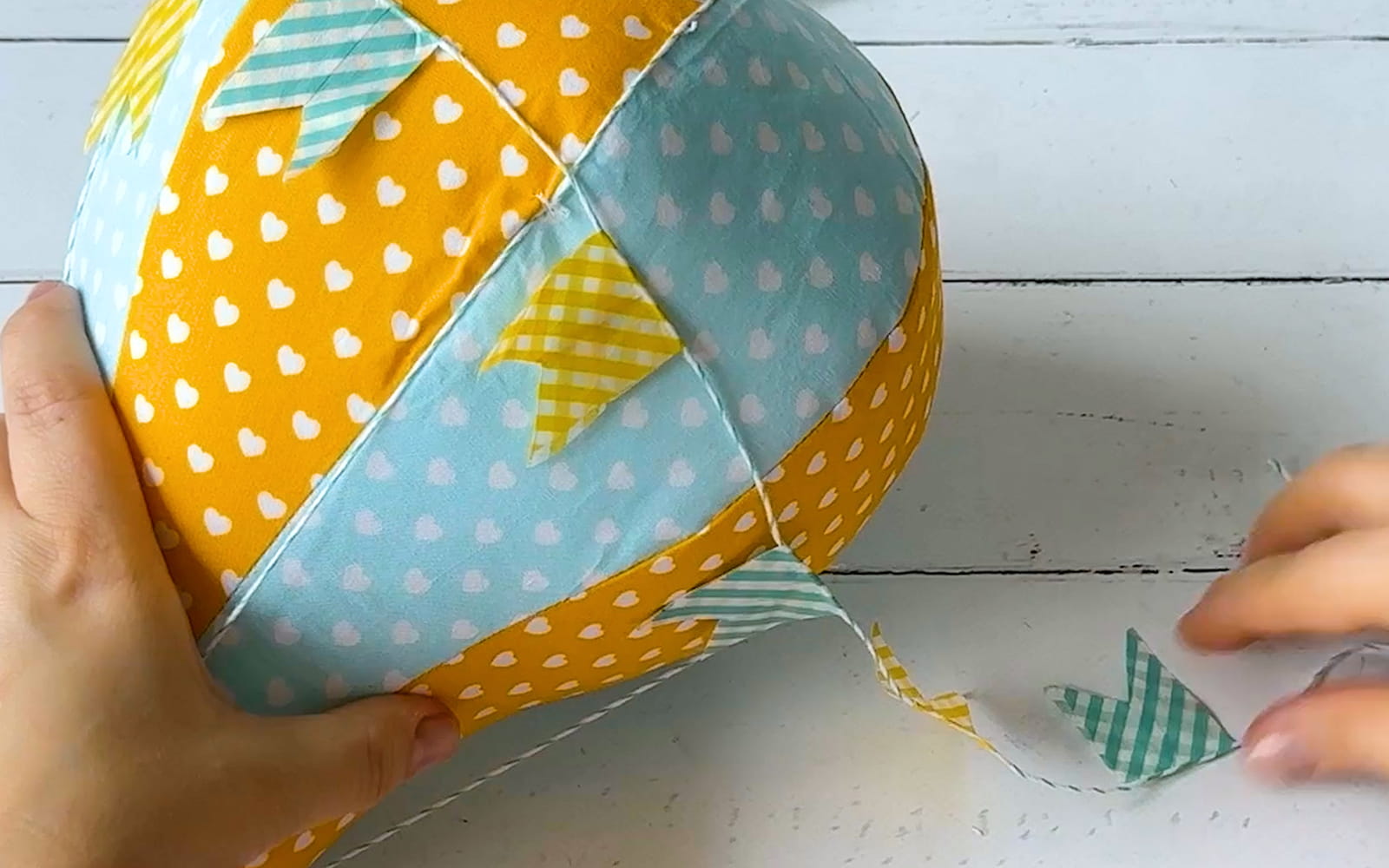 Washi tape bunting being tied to stuffed toy hot air balloon.
