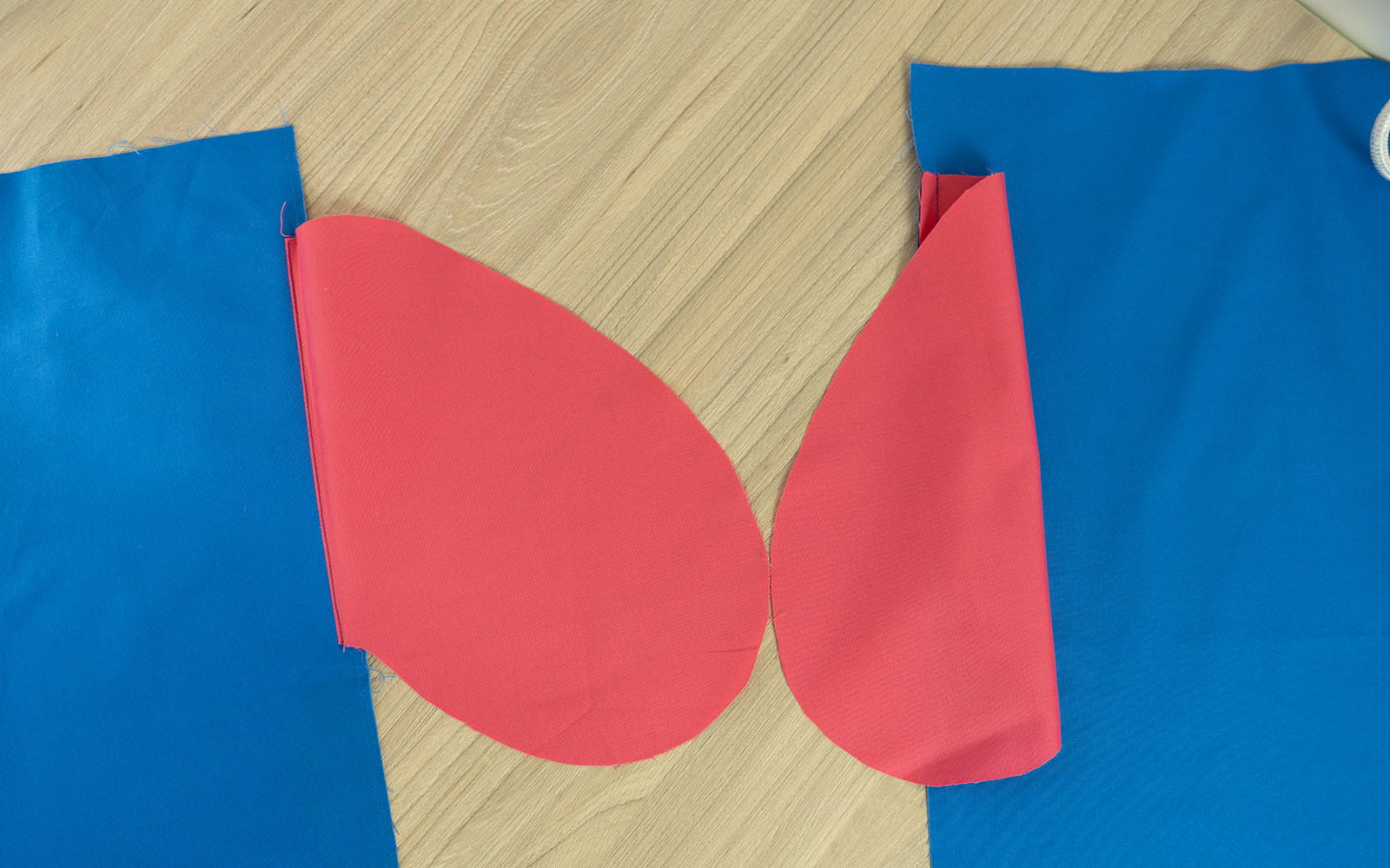 2 roze zakken vastgenaaid aan blauwe stof op houten ondergrond 