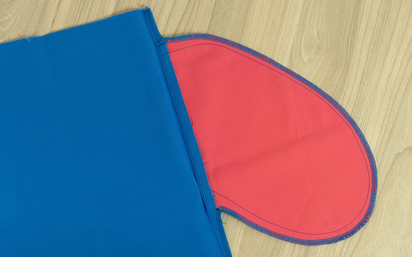 Afgewerkte roze zak vastgenaaid aan blauwe stof op houten ondergrond 
