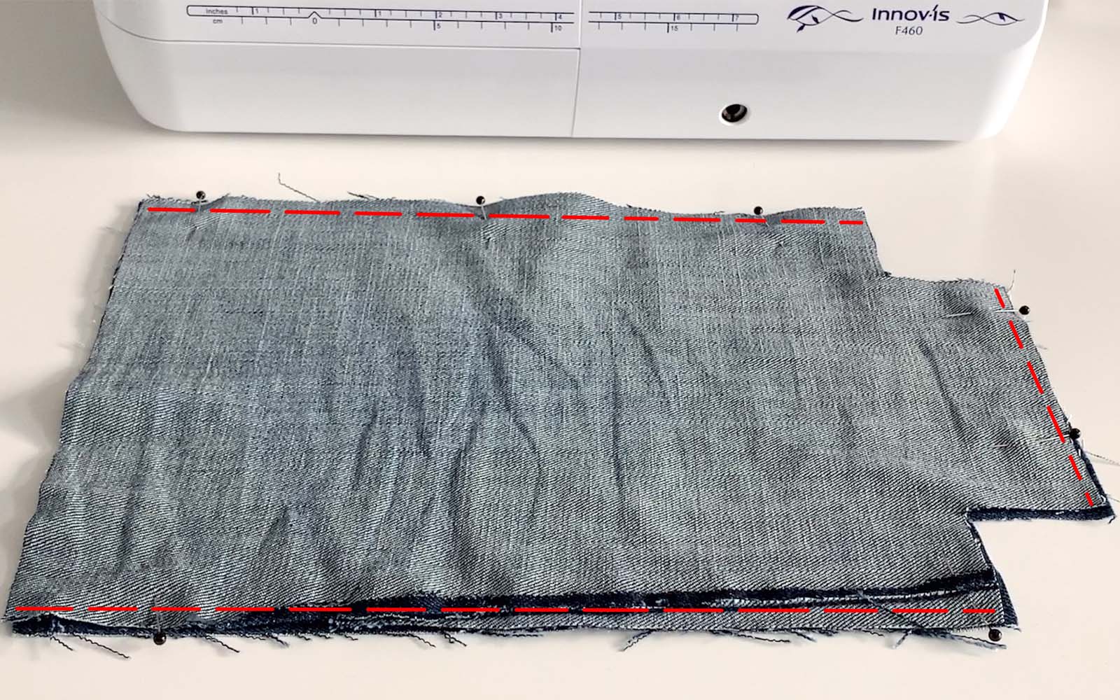 Square piece of blue denim with red sewing line marked on