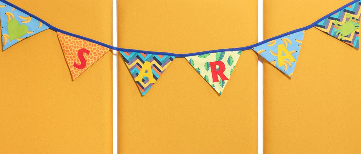 bunte Geburtstags-Wimpelkette mit text „Sara“ auf gelbem Hintergrund