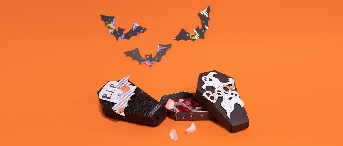 Black card coffin with sweets in on orange background