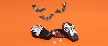 Schwarzer Kartensarg mit Süßigkeiten auf orangefarbenem Hintergrund