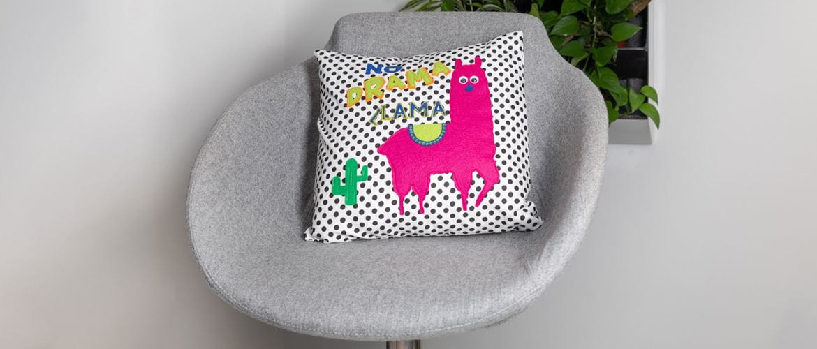 Spotty cushion with pink llama on grey chair