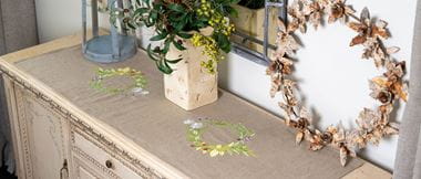 brown linin table runner with green herb wreath embroidered twice