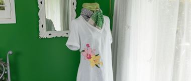 white linen dress with orchid embroidery on mannequin against green wall