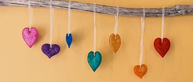 Hearts hanging from driftwood on yellow background